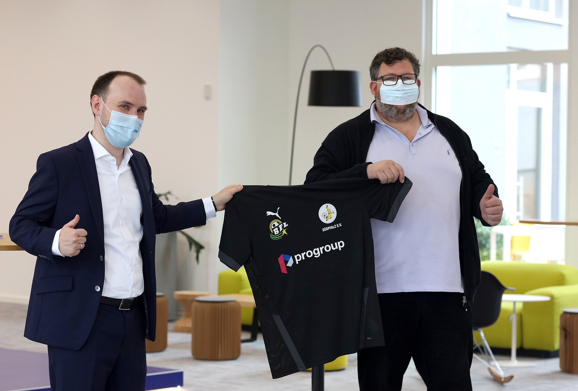 Maximilian Heindl, Chief Development Officer und Mitglied des Vorstands von Progroup, und Stefan Schmitzer, Vorsitzender des Vereins Team Bananenflanke Südpfalz e.V., freuen sich über die neuen Trikots für die Mannschaft (v. l. n.)